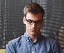 entrepreneur-startup-start-up-man-39866-39866 A young man in glasses writes in a notebook while sitting on a stylish couch indoors.
